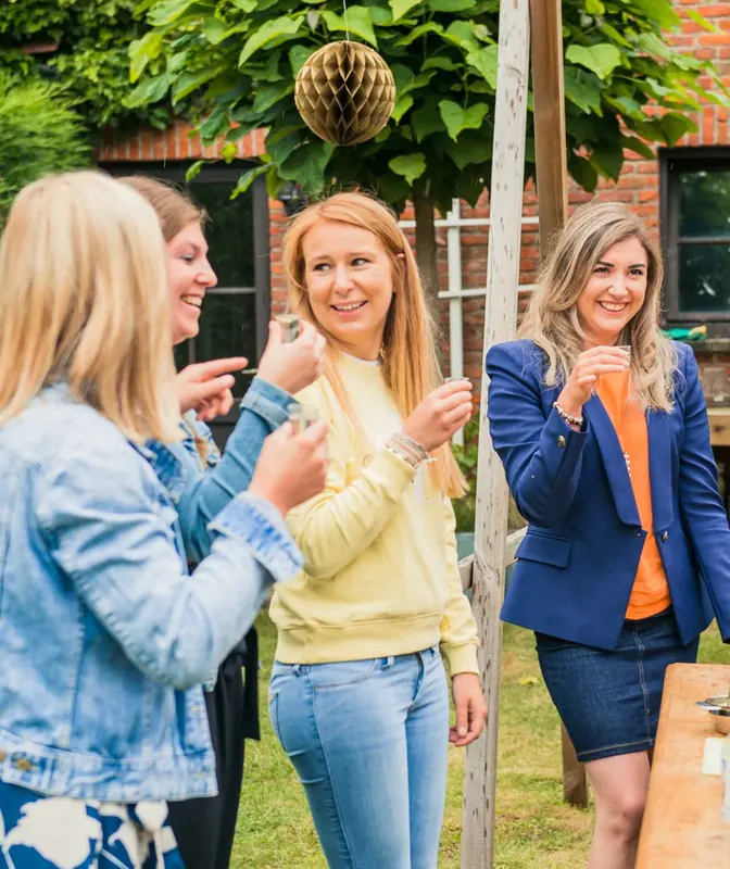 Collega’s klinken samen in de tuin tijdens een cocktailworkshop