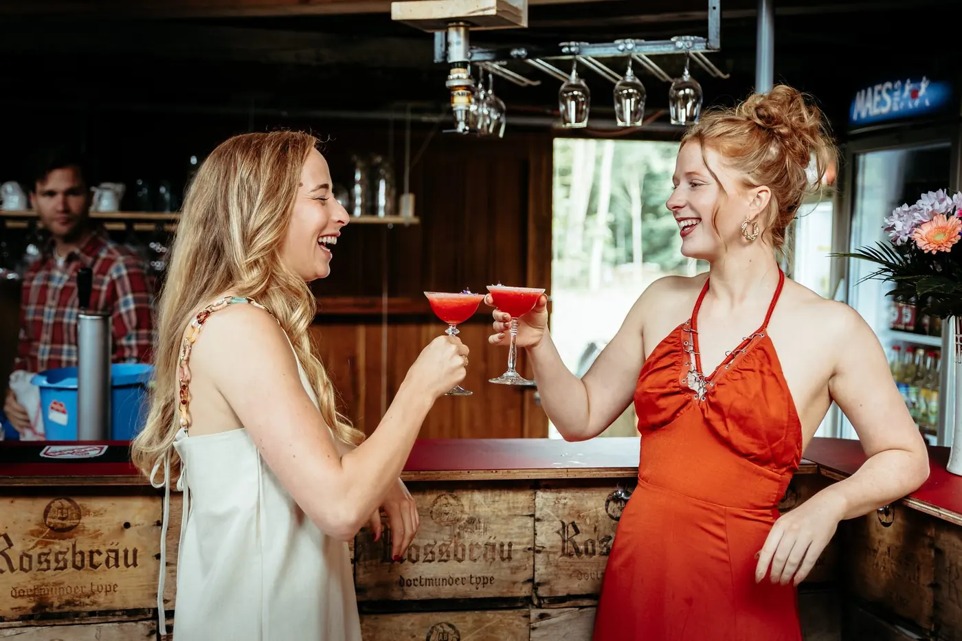 Twee vriendinnen klinken met rode cocktails aan de bar